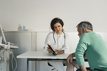 &Auml;rztin sitzt mit Patient im Wartezimmer und bespricht Ergebnisse