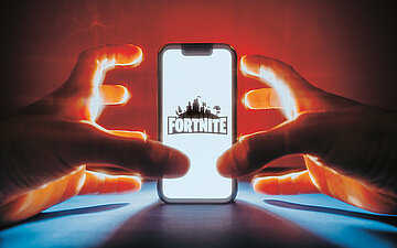Foto eines Kindes, das am Smartphone Fortnite spielt. Es sind nur die H&auml;nde zu sehen.