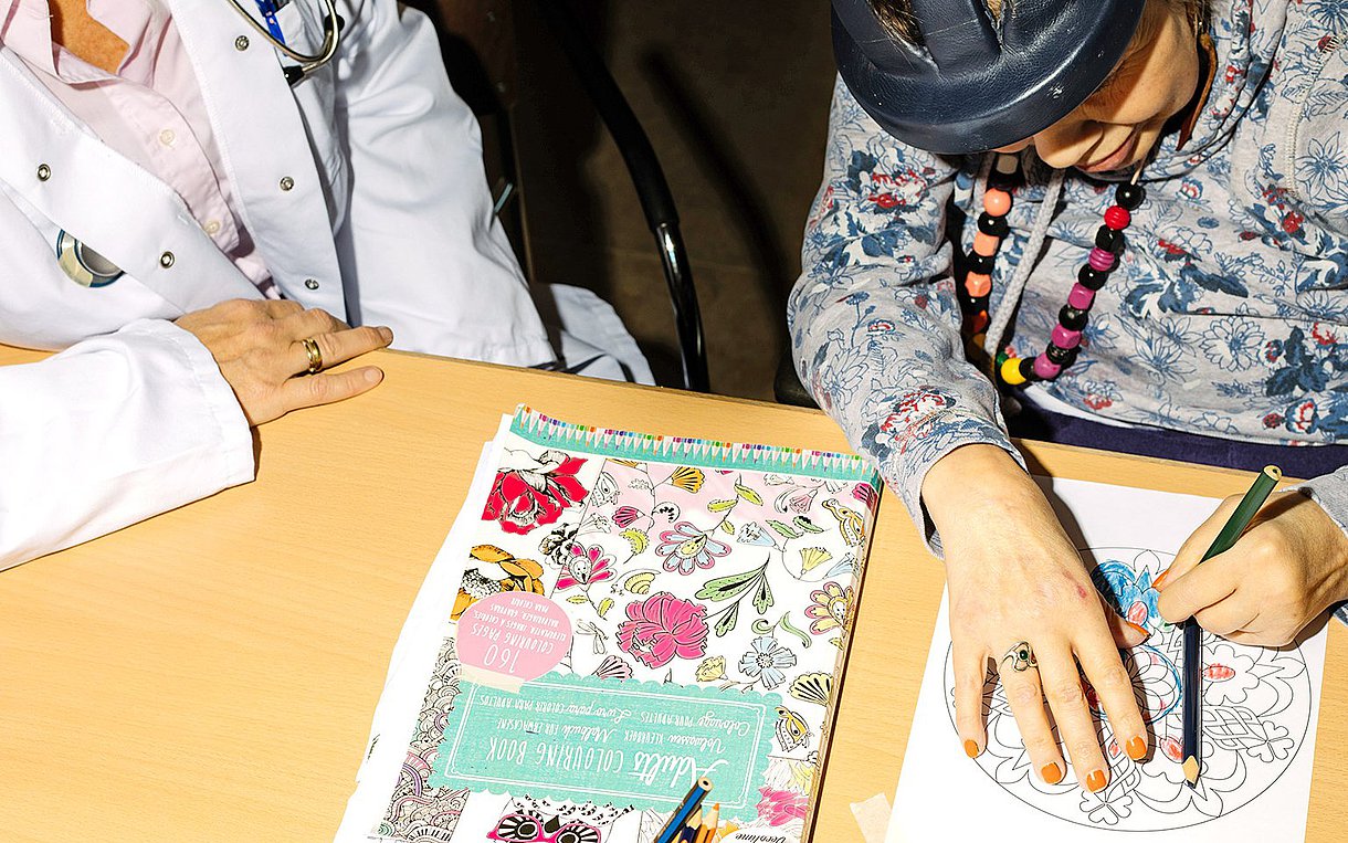 Foto von Tanja Sappok, die neben einer behinderten Patientin sitzt, die ein Mandala ausmalt