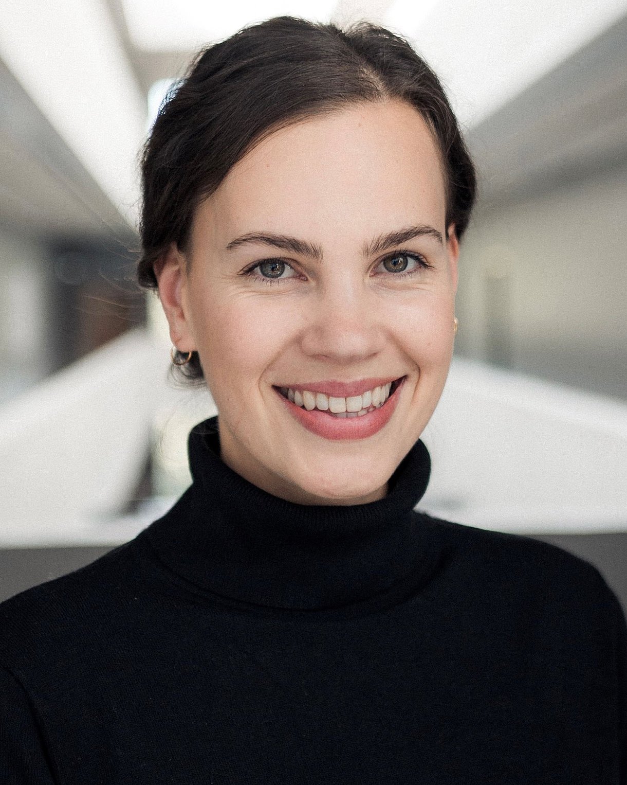 Foto: Simona Schick, gescheiteltes nach hinten gebundesnes dunles Haar, schwarzer Rollkragen-Pullover