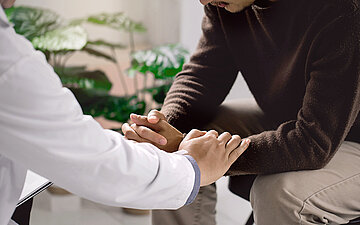 Foto: Ein Arzt h&auml;lt einen Patienten mitf&uuml;hlend die H&auml;nde.