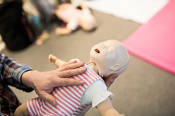 Elias Becker zeigt an einer Puppe, wie man bei Kindern Erste Hilfe leisten kann