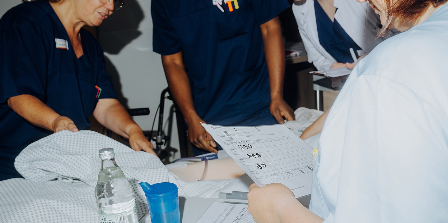 Foto: Arbeitszene aus dem Room of Errors – (angehende) Mediziner stehen um die Simulationspuppe herum.
