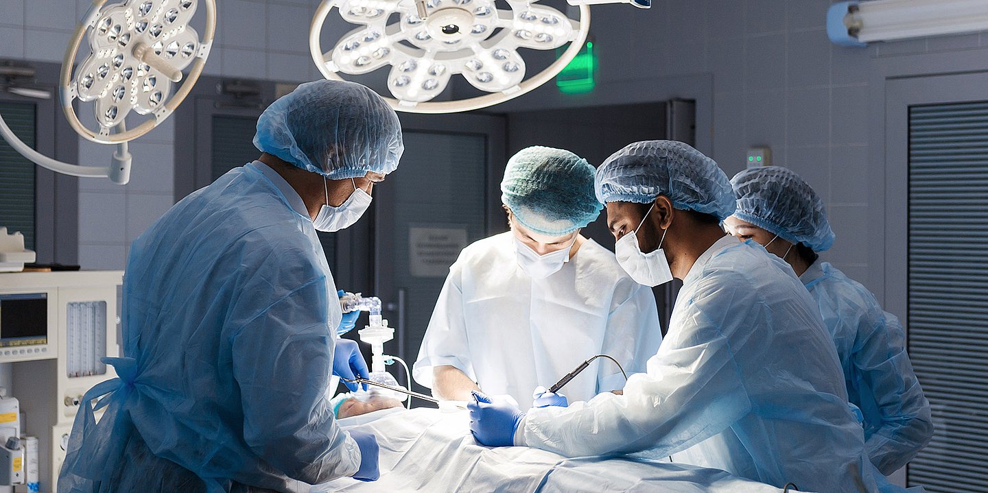 Vierköpfiges Team in OP-Kleidung bei der Arbeit, Blick in der OP-Saal