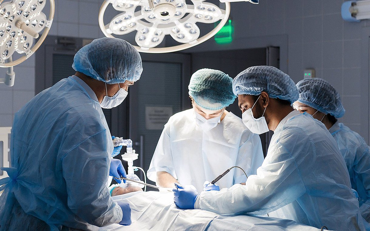 Vierköpfiges Team in OP-Kleidung bei der Arbeit, Blick in der OP-Saal