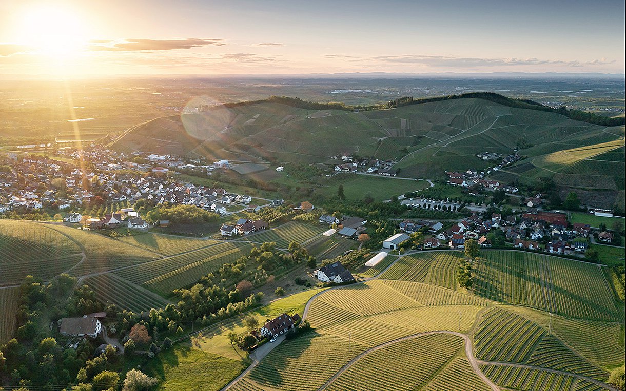 Foto: Eine Landschaftsaufnahme von einer dörflichen Umgebung im Sonnenuntergang.