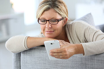 Das Foto zeigt eine Frau, die auf ihr Smartphone schaut
