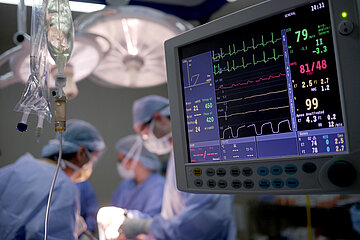 Ein Monitor in Nahaufnahme zeigt die Vitalwerte w&auml;hrend einer Operation im Hintergrund.