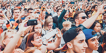 Foto: Eine Menschenmenge mit Deutschlandfahnen und -schals reckt die H&auml;nde in die H&ouml;he und jubelt.