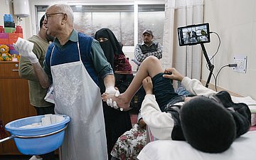 Ein junger Patient liegt auf der Liege im Behandlungszimmer und bekommt einen Gipsverband.