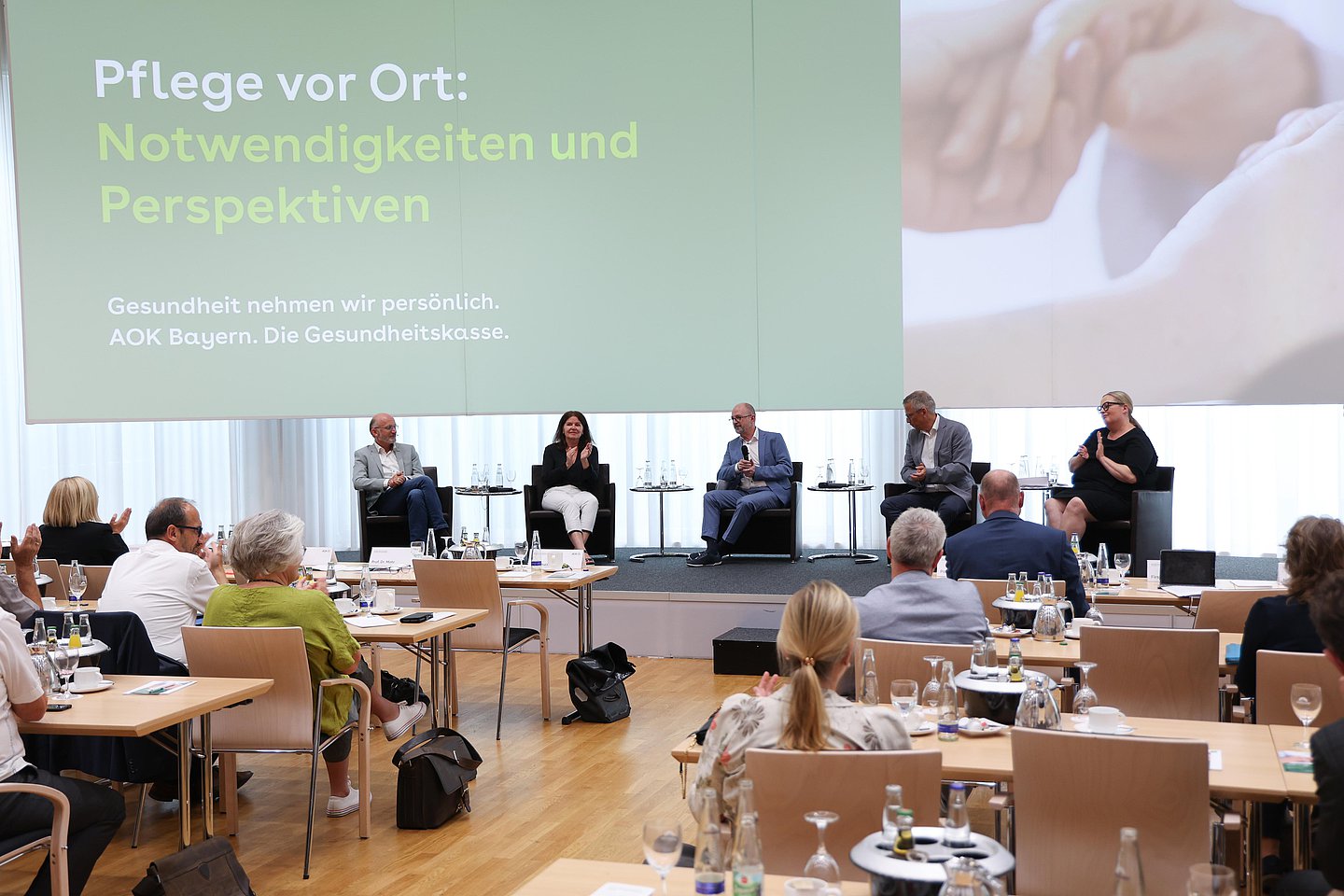 Auf dem Podium diskutieren Expertinnen und Experten bei einer Veranstaltung der AOK Bayern in München über neue Wege in der Pflege.