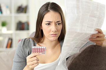 Antibaby-Pille Eine junge Frau liest den Beipackzettel der Antibaby-Pille
