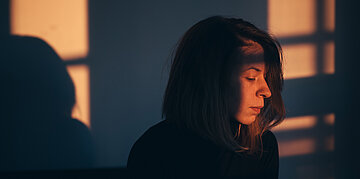 Foto: Gesicht einer Frau im Schatten.