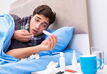 Gesundheitsreport: Erkältungen in Westfalen-Lippe Foto zeigt einen kranken Mann, der mit Fieber im Bett liegt und einen grippalen Infekt auskuriert..