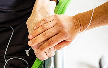 Foto: Hand eines Angestellten auf der Palliativstation greift die Hand eines Patienten.
