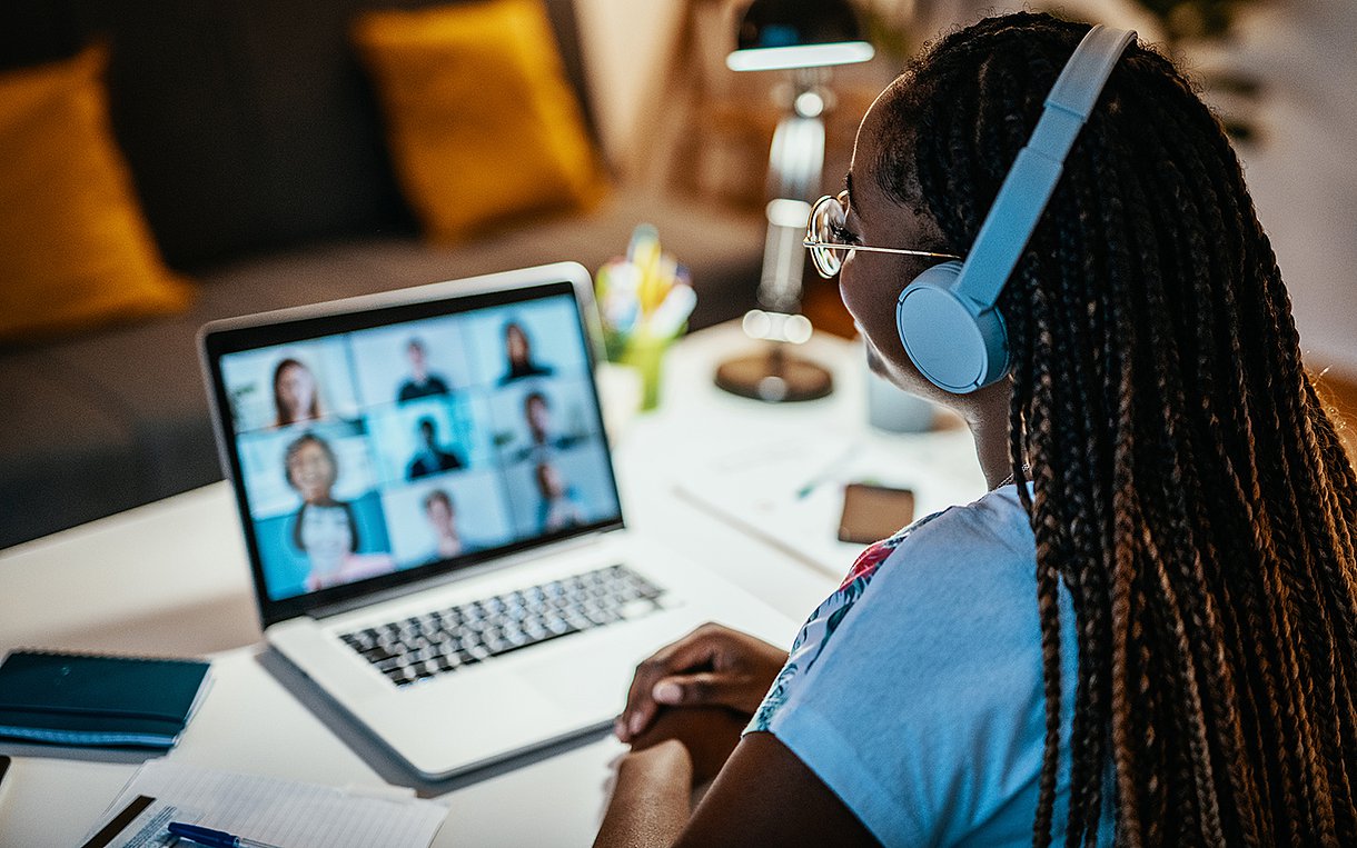 Eine Pflegekraft sitzt am Tisch mit Kopfhörern und lernt am Laptop über die AOK Pflege Mediathek.