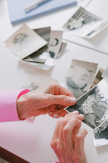 Symbolbild Demenz: Alte Frauenh&auml;nde halten alte Fotos, die undeutlich werden.