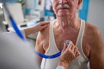 Krankenhaus-Report 2025 Westfalen-Lippe Ein älterer Mann in Nahaufnahme wird von einem Arzt abgehört.