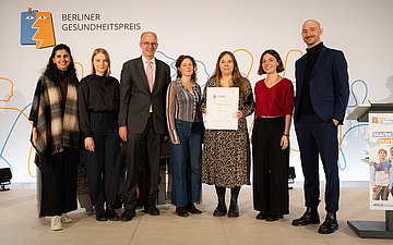 Foto: 1. Preis – Dare to Care Gruppenfoto mit sechs Personen: Preisträger mit Michael Brand (CDU, 3.v.l.), Parlamentarischer Staatssekretär im Bundesministerium für Bildung, Familie, Senioren, Frauen und Jugend