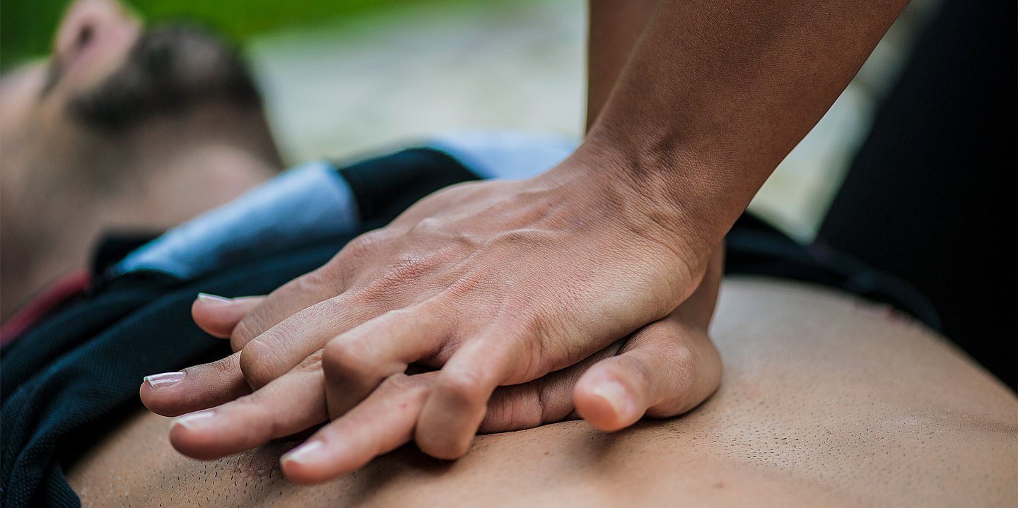 Foto: Zwei Hände führen eine Herz-Druck-Massage auf dem Brustkorb eines Mannes aus.
