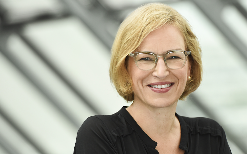 Poträt: Dr. Katrin Krämer, Abteilungsleiterin Versorgungsmanagement im AOK-Bundesverband, blonde Brillenträgerin in schwarzer Bluse mit V-Ausschnitt 