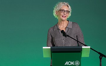 Eine Frau hält eine Rede hinter einem Rednerpult.