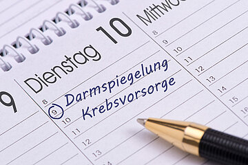 Ein Spiralkalender im Querformat zeigt das Datum 'Dienstag 10' an. Dort ist um 9 Uhr ein Termin 'Darmspiegelung/Krebsvorsorge' eingetragen.