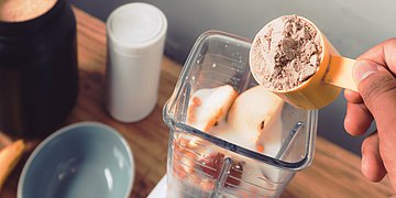 Nahrungsergänzungsmittel Eine Person schüttet Nahrungsergänzungsmittel in einen Mixer.