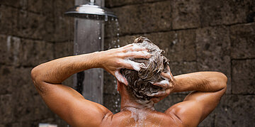 Foto: Ein Mann steht unter der Dusche und w&auml;scht sich gerade die Haare.