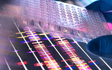 Ein Laborger&auml;t und bunte DNA-Muster auf einem Bildschirm