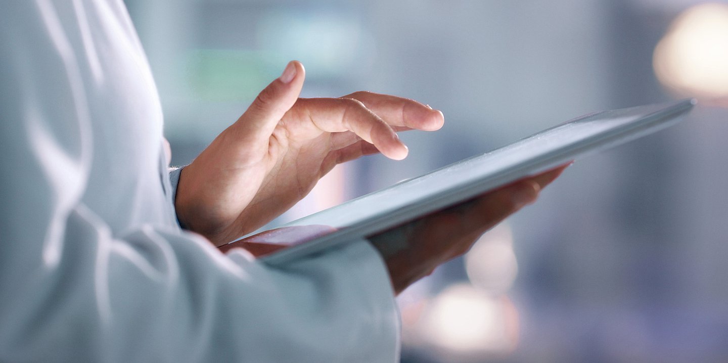 Eine &Auml;rztin tippt auf einem Tablet.