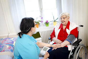 Eine Pflegerin misst den Blutdruck einer Pflegebed&uuml;rftigen