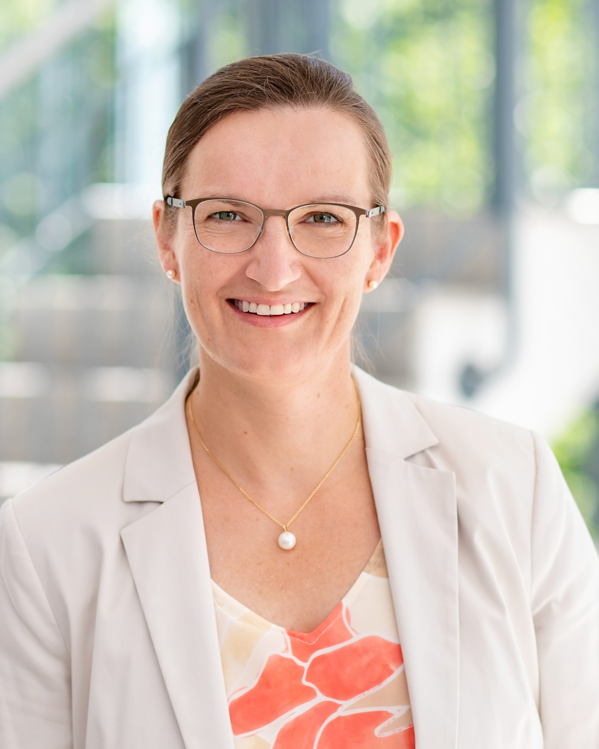 Foto: Dr. Susanne Kuger vom Deutsches Jugendinstitut, Leiterin des Zentrums für Dauerbeobachtung und Methoden, trägt eine ornage-gelb-beige gemusterte Bluse und einen beigen Blazer. Sie ist Brillenträgerin mit brünetten Haaren.