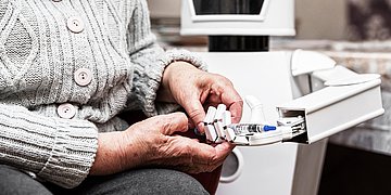 Ein Roboter reicht einer älteren Pflegebedürftigen ein Medikament.