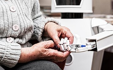 Ein Roboter reicht einer &auml;lteren Pflegebed&uuml;rftigen ein Medikament.