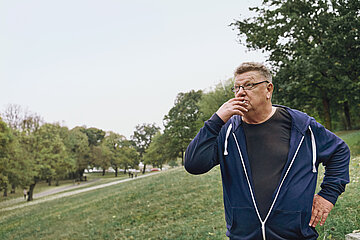 Ein Mann steht im Park und raucht