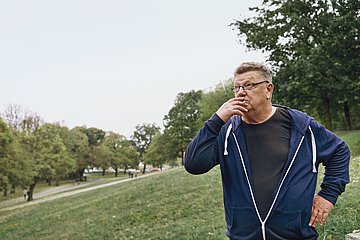 Ein Mann steht im Park und raucht