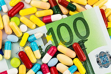 Arzneimittel Auf dem Foto ist ein 100 Euro-Schein mit vielen verschiedenen Tabletten abgebildet.