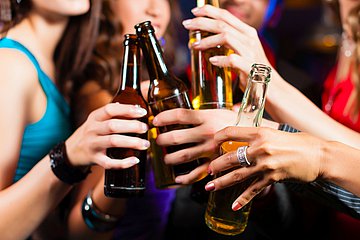 Alkoholfasten in Westfalen-Lippe Foto einer Gruppe von jungen Menschen, die gemeinsam feiern und mit mit Flaschen in der Hand Flaschen zusammen anstoßen.