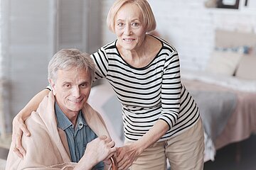 &Auml;ltere Dame unterst&uuml;tzt ihren Mann beim Aufstehen