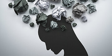 Foto: Illustration eines Kopfes &uuml;ber dem sich viele zerkn&uuml;llte Papierzettel ballen.