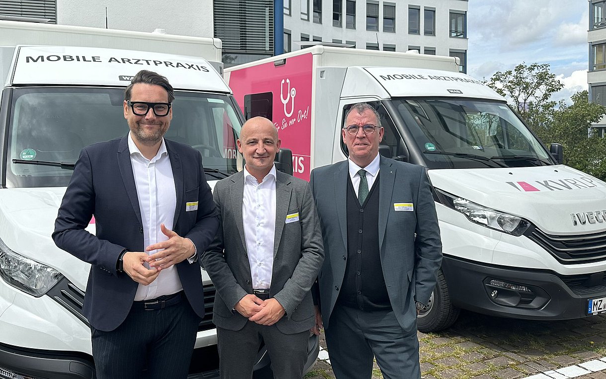 Vertreter von Kassen und Ministerium vor zwei Mobilen Arztpraxen
