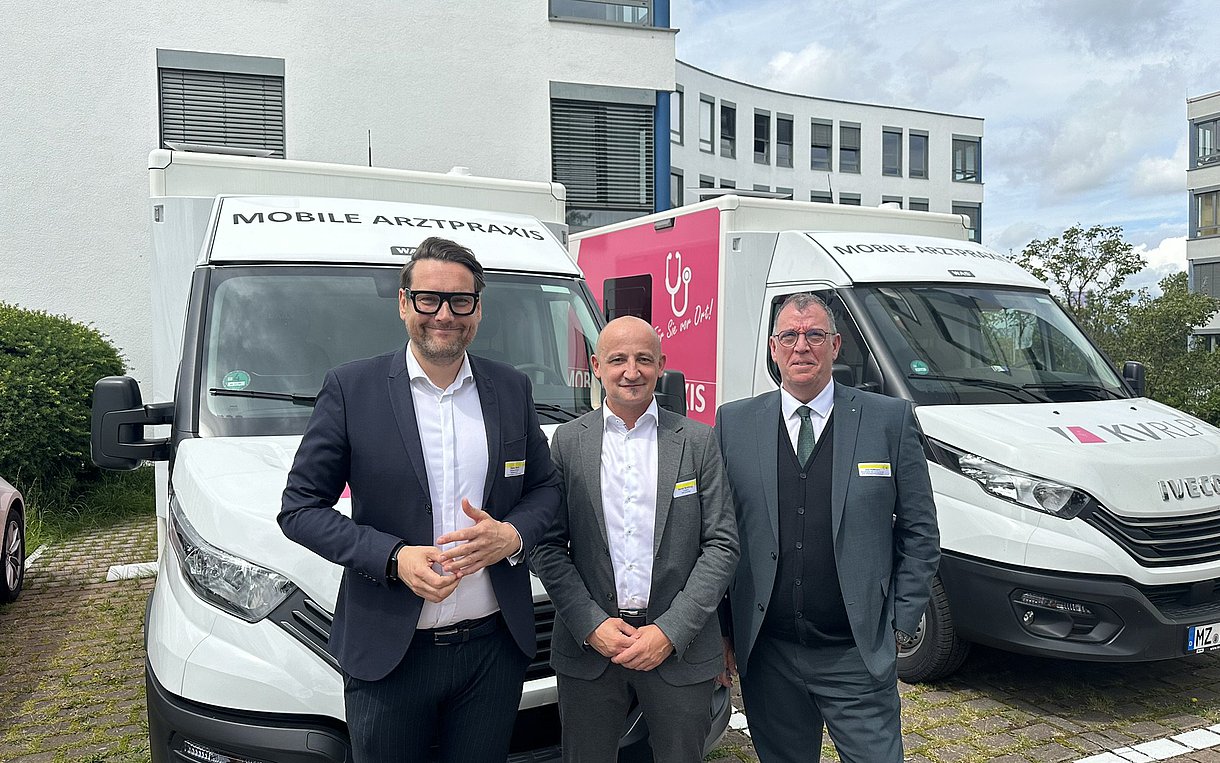 Vertreter von Kassen und Ministerium vor zwei Mobilen Arztpraxen