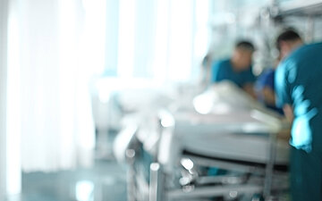 Foto: Ein Klinikteam versorgt gemeinsam eine Person im Krankenbett.
