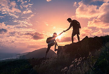 Foto zeigt zwei Bergsteiger auf dem Berg im Sonnenuntergang oder aufgang