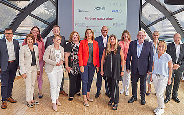 Foto von den die Projektpartner, u.a. die Vorst&auml;ndin der AOK RPS, Dr. Martina Niemeyer (3. v. li). und die Caritasdirektorin Stefanie Krones (6. v. li) in Anwesenheit von MdB Tanja Machalet (4. V. li).