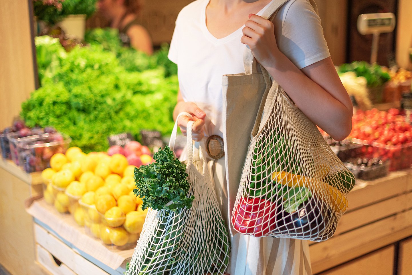Das Bild zeigt eine Frau beim Einkauf von Obst und Gemüse.