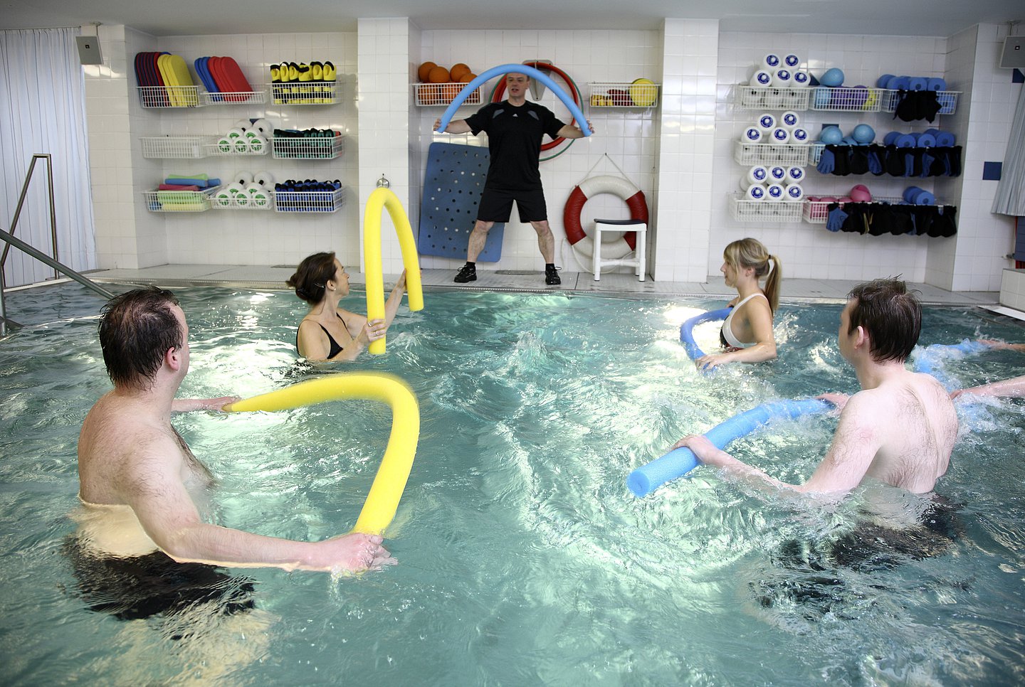 Foto: Vier Patienten machen Aquagymnastik unter Anleitung eines Trainers.