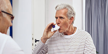 Ein COPD-Patient benutzt w&auml;hrend der Untersuchung beim Arzt einen Spacer, um die Atmung zu erleichtern.