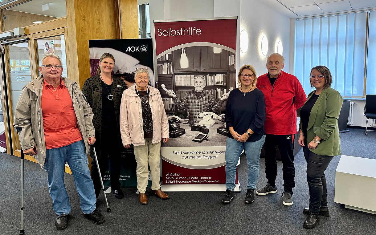 Das Foto zeigt (v.l.) Karl Huss (Selbsthilfegruppe Diabetes), AOK-Kundencenterleiterin Susanne Engelhardt, Doris Niemann (Selbsthilfegruppe Recover), Sigrun Ruck (Leitung des Selbsthilfenetzwerkes Neckar-Odenwald), Walter Gellner (Selbsthilfegruppe Morbus Crohn & Colitis ulcerosa) und Kristina Haase (Sozialer Dienst der AOK) vor einem der neun Rollups.